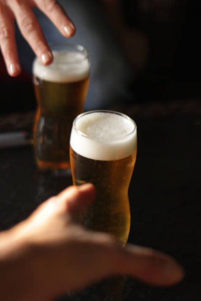 istock Two women hands over a glass of light beer 1089832038