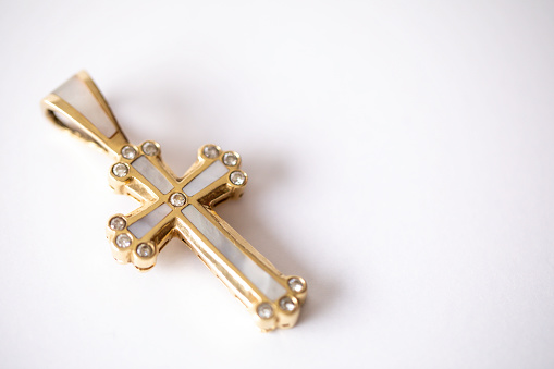 Gold, diamond, and pearl cross necklace pendant on a white background