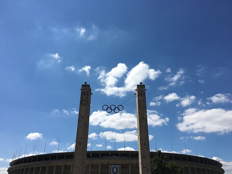 Berlin, Germany - July 15, 2018: The Olympic Stadium (Olympiastadion) in Berlin on a sunny summer day. The Olympiastadion of Berlin was built for the 1936 Summer Olympics. During the Olympics, the record attendance was thought to be over 100.000. Today the stadium is part of the Olympiapark Berlin. Since renovations in 2004, the Olympiastadion has a permanent capacity of 74.475 seats and is the largest stadium in Germany for international football matches.
