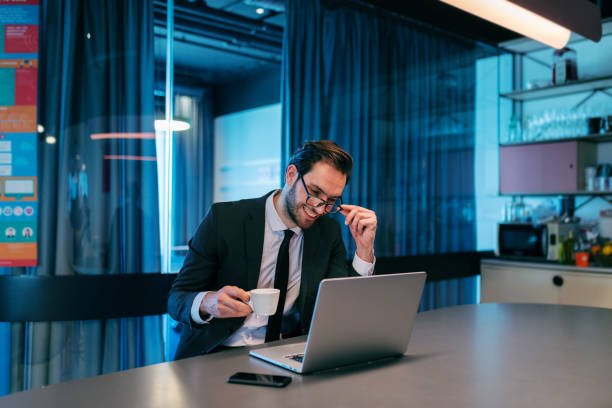 istock Happy businessman having coffee pause on work and sitting on the counter, drinking coffee, using laptop. 1089839770