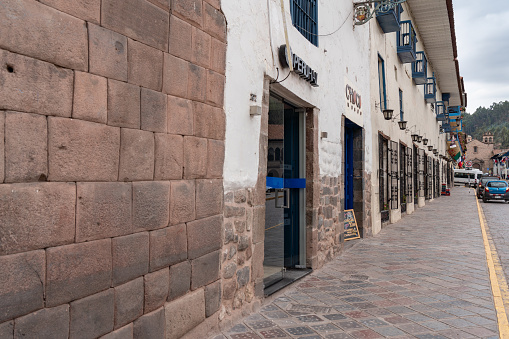 Cusco, Peru - Oct 17, 2018: Shops window beside the street.  A narrow street in central Cusco with old colonial architecture, cobblestone roads, and some people walking.