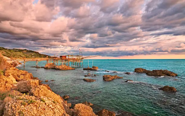 Rocca San Giovanni, Chieti, Abruzzo, Italy: landscape of the Adriatic sea coast at dawn with a typical Mediterranean fishing hut trabocco, under a dramatic cloudy sky