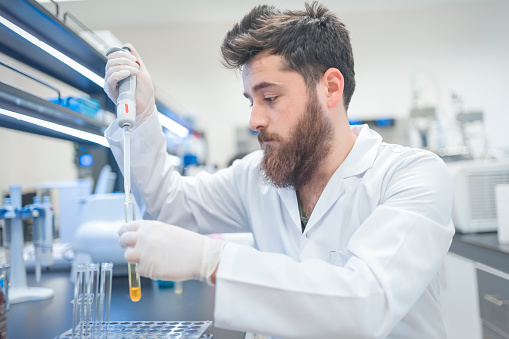 Young male tech or scientist loads sample with automatic pipette