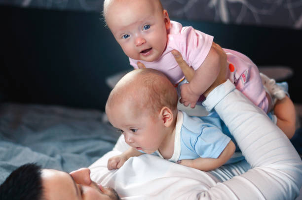 istock Young father with his newborn twins lying in bed. Selective focus. 1089852246