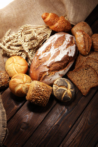 istock Different kinds of bread and bread rolls on board from above. 1089855104