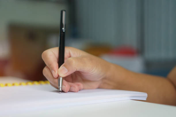 istock Business Concept : Hand Businessman holding silver pen to taking notes on white paperwork or Document at conference meeting room in seminar on indoors blur people background 1089898402