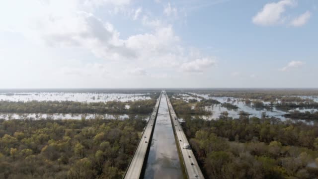 Aerial Drone Shot of Flying over Breaux Bridge (Interstate 10) and the Atchafalaya River Basin Swamp Surrounded by Cypress Tree Forests in Southern Louisiana Under a Sunny but Partly Cloudy Sky
