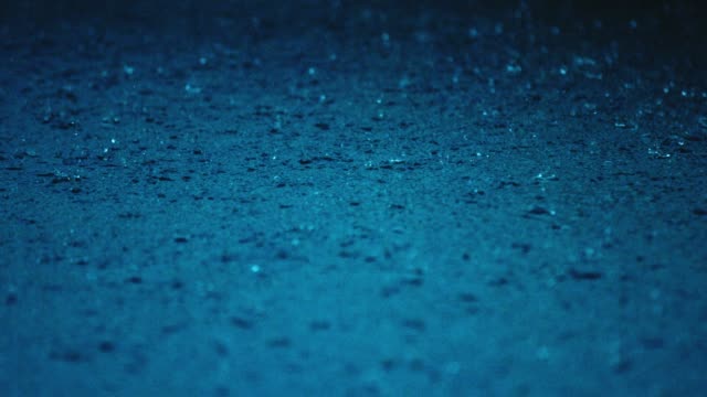 Rain Water Droplets Splash into a Blue Puddle