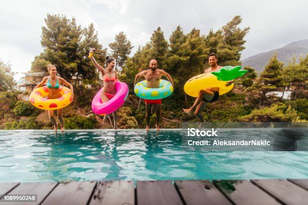 Friends Are Jumping Into The Pool Stock Photo - Download Image Now - Swimming Pool, Summer, Friendship