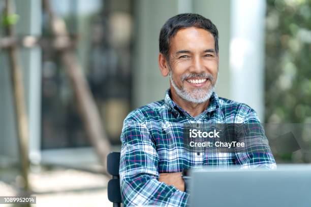 Portrait Of Happy Mature Man With White Grey Stylish Short Beard Looking At Camera Outdoor Casual Lifestyle Of Retired Hispanic People Or Adult Asian Man Smile With Confident At Coffee Shop Cafe Stock Photo - Download Image Now