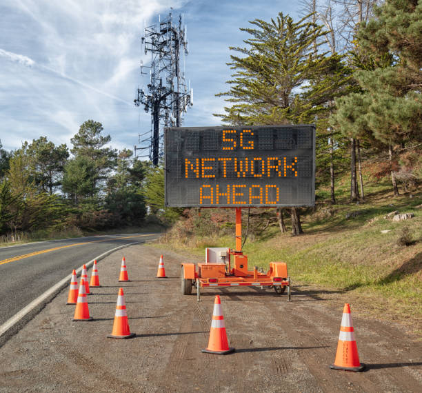 istock 5G communications tower for mobile phone: Roadside warning sign on rural road. 1089968136
