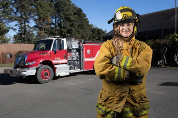 Woman firefighter by firetruck: Portrait looking at camera in rural California
