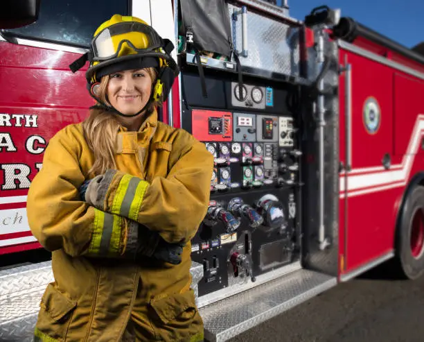 Woman firefighter by firetruck: Portrait looking at camera in rural California