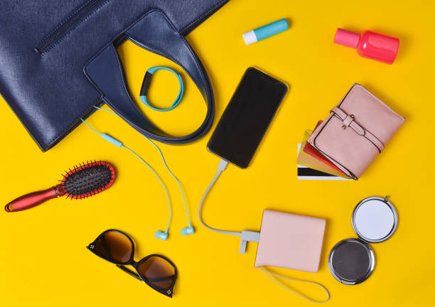 istock Women's accessories are laid out on a brightly orange surface. Bag, cosmetics, smartphone, smart watch, external battery, headphones, wallet with credit cards. What's in the women's bag? Top view. 1089976164