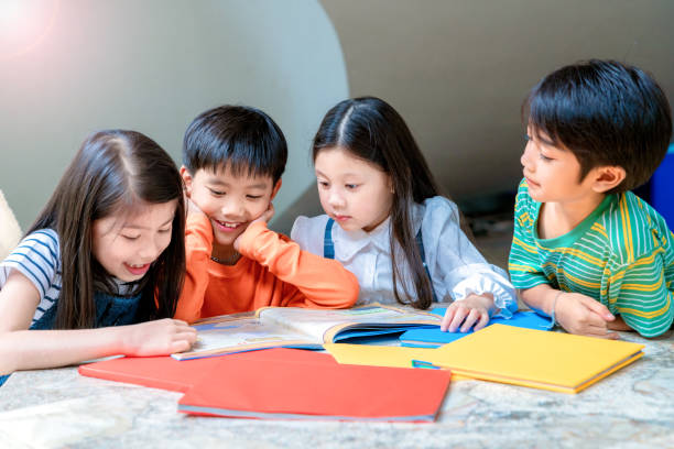 アジアの小さな子供たちが陽気な本を読んで - 子供時代 ストックフォトと画像
