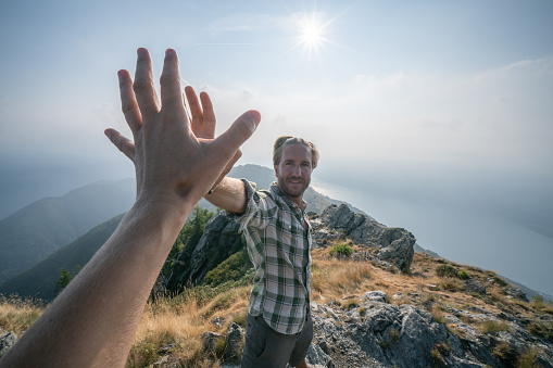 Two hikers celebrating on mountain trail with a high five. Shot in Switzerland, Springtime.