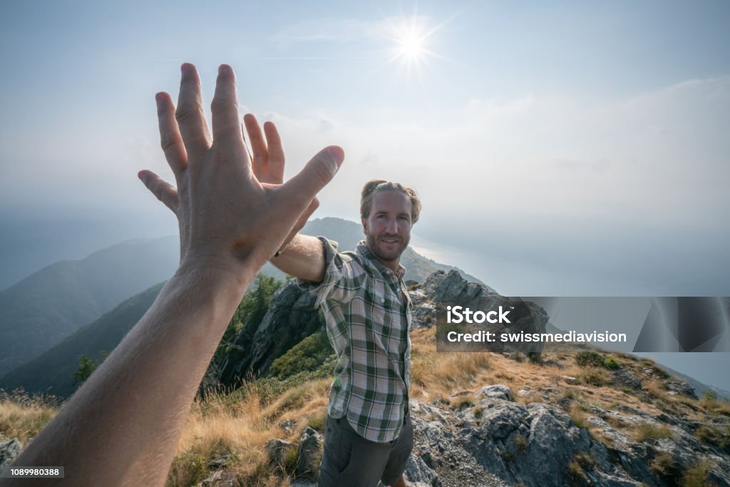 Personal perspective of Two hikers celebrating on mountain top with a high five Two hikers celebrating on mountain trail with a high five. Shot in Switzerland, Springtime. Point of View Stock Photo