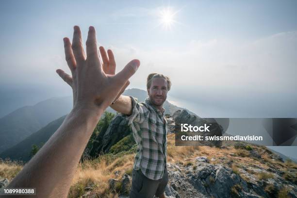 Personal Perspective Of Two Hikers Celebrating On Mountain Top With A High Five Stock Photo - Download Image Now