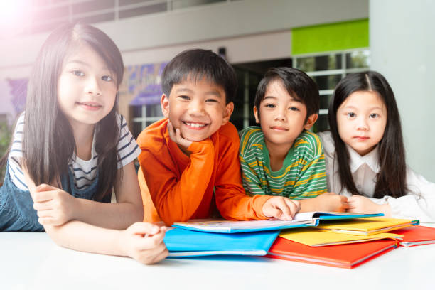 азиатские маленькие дети чтение книги веселый - asian ethnicity child little boys education стоковые фото и изображения