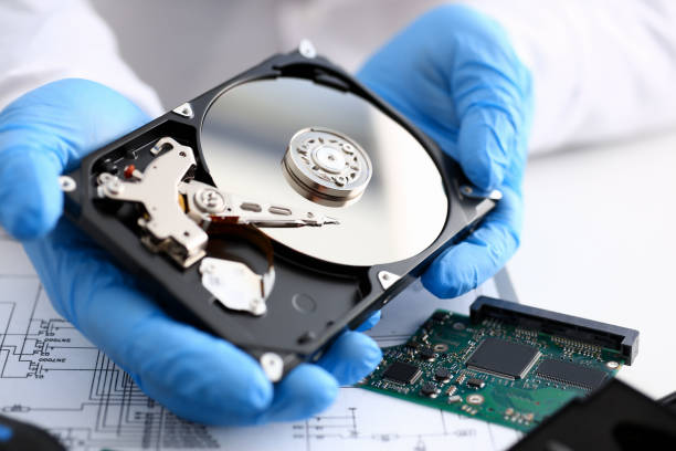 Male repairman wearing blue gloves holding Male repairman wearing blue gloves holding hard drive from computer or laptop in hands. Performs fault diagnostics and performs urgent repairs recovery of lost data during deletion HDD closeup hard drive stock pictures, royalty-free photos & images