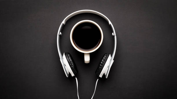 istock Coffee in white mug and white headphones on a black background. Top view, copy space 1089987418