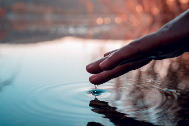 палец касается поверхности горного озера. отражение руки - reflection on the water стоковые фото и изображения