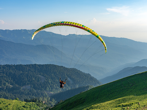 Paraglider flying over town and bir billing mountains. beautiful view of bir-billing mountains paragliding site in himachal pradesh.