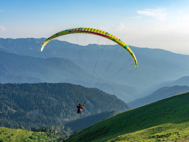 yellow paraglider in blue clear sky over the green mountain - airplane sky extreme sports men imagens e fotografias de stock