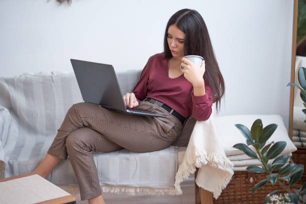 istock Pretty young woman working on a laptop while drinking cup of tea 1090024810