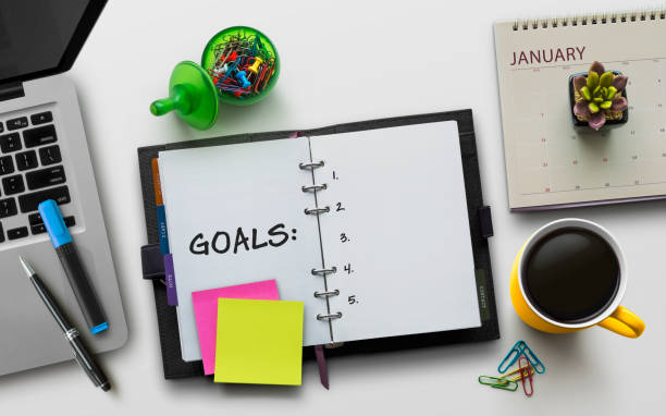 istock New Year goals, resolution or action plan concept. Notebook on table with laptop, calendar, coffee, plant and stationery. Flat lay (top view) notepad for input copy or text on white background. 1090029282