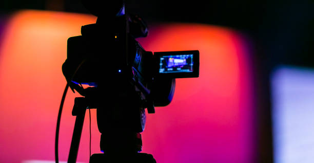 Silhouette of a TV Camera filming a live broadcast Silhouette of a TV Camera filming a live broadcast film crew photos stock pictures, royalty-free photos & images