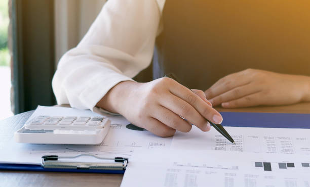 istock Businesswoman analyzing investment charts and pressing calculator buttons over documents. Accounting Concept. 1090035098