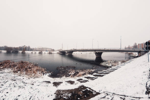 istock River Bank Covered In Snow With Sturdy Bridge Against Overcast Sky 1090036642