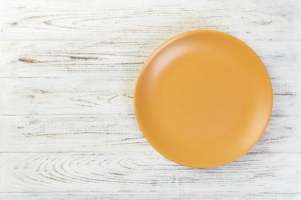 istock Directy above Empty orange matte plate on white wooden background with copy space 1090049116