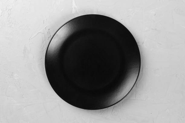 istock Top view of matte round empty dark dish on grey cement background space for you design 1090049126