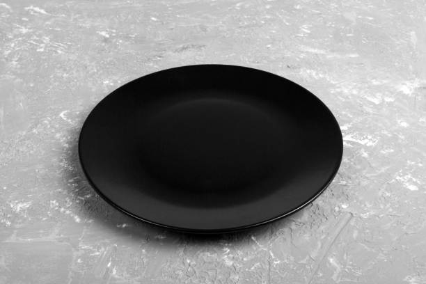 istock Top view of matte round empty dark dish on dark cement background copy space for you design. Perspective view 1090049144