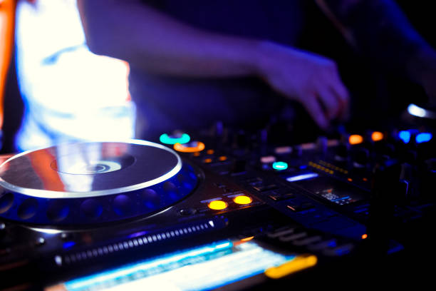 istock Disc Jockey mixing deck and turntables at night with colourful illuminated controls for mixing music for a party or disco 1090054696