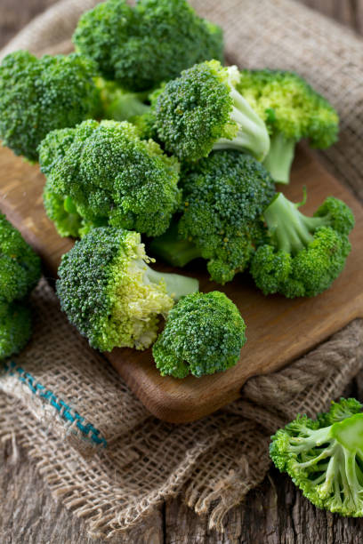 frischer brokkoli auf holzuntergrund - broccoli stock-fotos und bilder