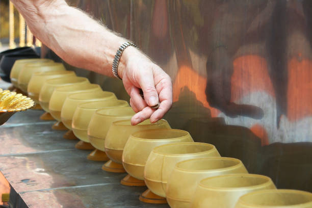 istock Man putting coins in monk's alms bowl. 1090069844