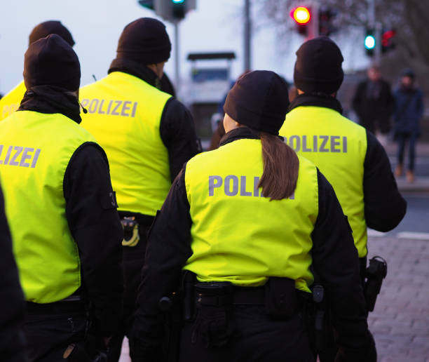 Group of German police officers in black uniforms and hi-viz vests saying "Police" in German patrolling the christmas market stock photo