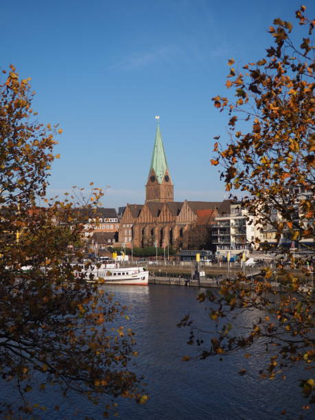 Bremen, Germany - River Weser with St. Martini church framed by trees in the foreground with slanted horizon stock photo