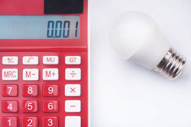 istock Energy-saving light bulbs, a calculator and a notebook with a pen are on the white table 1090082808
