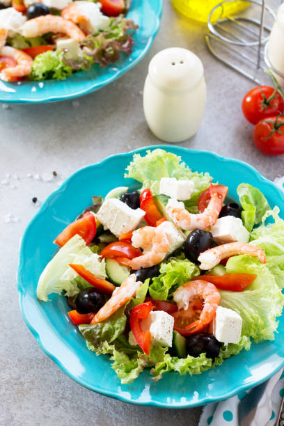 the concept of healthy and dietary food. greek salad with shrimps and vegetables on a light stone or slate table. - 11275 imagens e fotografias de stock