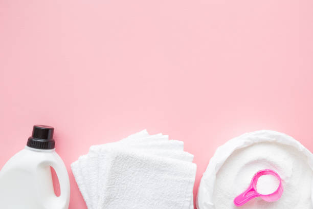 istock White powder with cup or scoop in plastic pack. Liquid detergent bottle and towels. Fabric softener. Regular clothes washing. Top view. Empty place for text or logo on pastel pink background. 1090086904