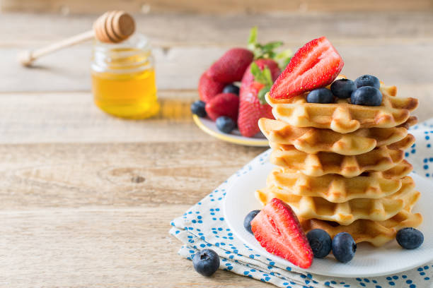 istock Stack of waffles with blueberries and strawberries on wooden background 1090097950