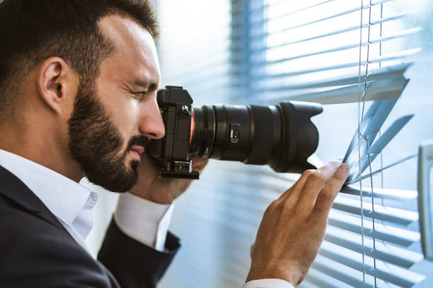 istock The man with a camera photographing through the blinds 1090104658