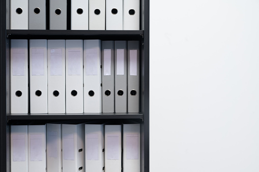 Blank blind folders with files in the shelf. Archival, stacks of documents in the book at the office with space for text