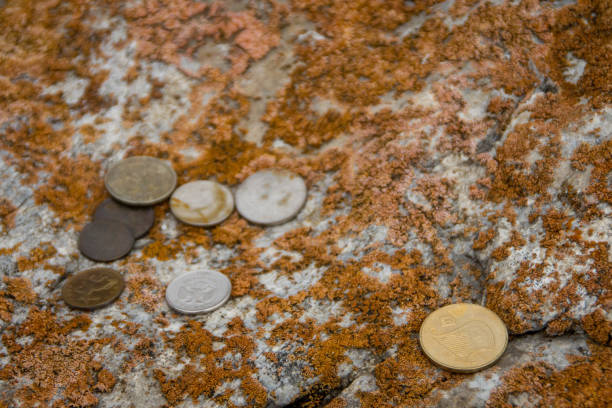 Background of European and beyond coins underwater that were tossed  into Lake Bled, Slovenia landing on a rock. Coins are thrown into Lake Bled near the island as a symbolic act of wishing for a return to Rome or for good fortune, based on a blend of Roman tradition and the legend of the bell on the island.