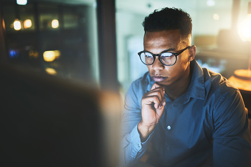 Cropped shot of a handsome young businessman looking thoughtful while working late at night in a modern office