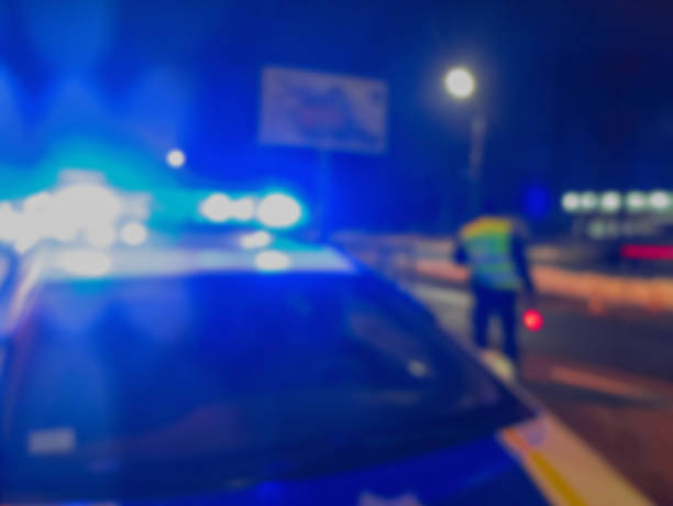неузнаваемые размытые огни полицейской машины и полицейский на фоне ночной дороги, место преступления, ночное патрулирование города. абст� - unrecognizable person flash стоковые фото и изображения